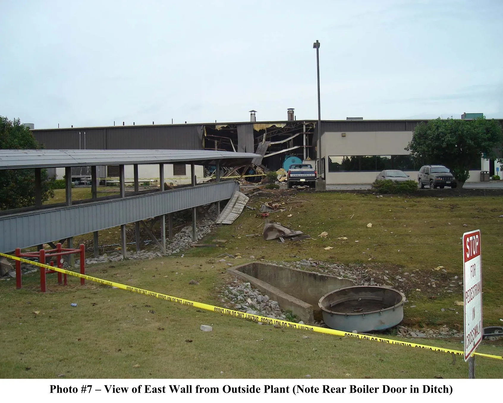 photo 7 - rear boiler door in near ditch with the damage facility exterior in the midground.